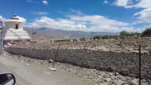Driving pass white chortens, big and small, standing aside of the road. Stock Footage 262297960