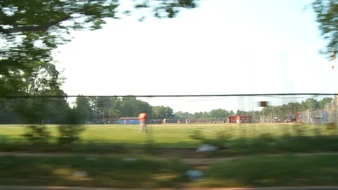 Driving passed baseball field in Queens, NY with young people playing, day. 스톡 동영상 107552451