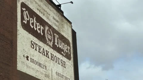 Driving past large Peter Luger sign steakhouse in Williamsburg Bridge NYC 스톡 동영상 148005237