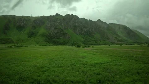 Driving past lush green meadows and jagged mountain range in Andoya Norway Vídeos de archivo 343131165