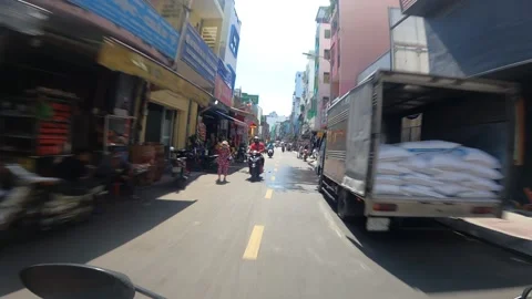 Driving past Motorbikes down narrow street in Ho Chi Minh City during the day Stock Footage 164680562