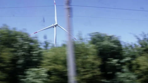 Driving past a spinning windmill with trees in the foreground. Stock Footage 157413004
