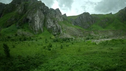 Driving past steep rocky mountain cliffs and green slopes in Andoya Norway Stock-Footage 343131232