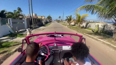 Driving pink convertible through Cuba slum 動画素材 172497397
