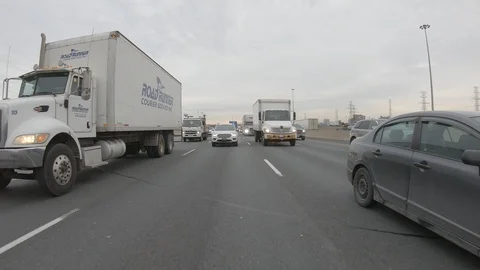 Driving plate POV reverse angle on highway with trucks cars and tractor trailers Stock Footage 100120305