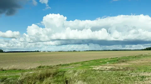 Driving plate side view of empty agriculture field under dramatic cumulus clouds 動画素材 345799422