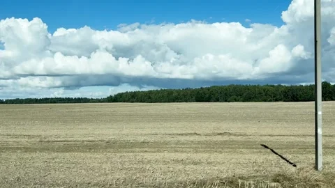 Driving plate side view of empty agriculture field under dramatic cumulus clouds 動画素材 345827333