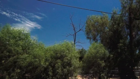 Driving POV across dusty desolate empty fence plots of land under blue sky Stock Footage 114881248