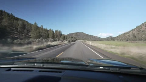 Driving POV through a green valley with pine covered hills in Oregon Stock Footage 346794788
