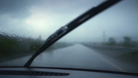 Driving in the rain, wipers on the windshield working, medium and close up shots Stockbeeldmateriaal 155945728