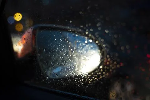 Driving at rainy night. reflection of rain drops at the car side mirror. city Stock Photos