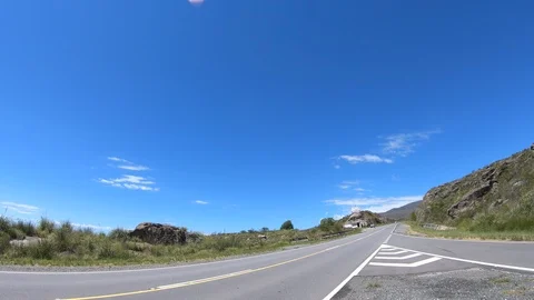 Driving on road making U turn and taking exit. Grasslands, rocky hills and woods 스톡 동영상 118628037