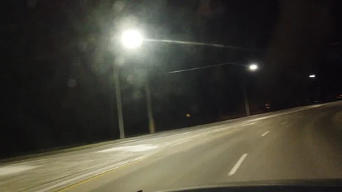 Driving On Road At Night On Angle With Red Sports Car Driving By And Overhead Stock Footage 109425080