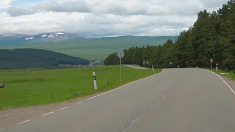 Driving on a scenic mountain road surrounded by green fields 库存影片 339501719