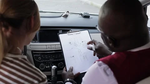 Driving school concept video. A car instructor teaches a young woman how to Stock Footage 206747375