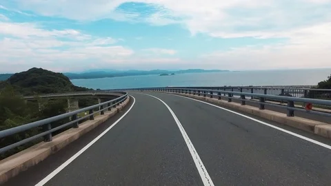 Driving shot of empty, straight road over ocean “Tsunoshima bridge” Video stock 77035091