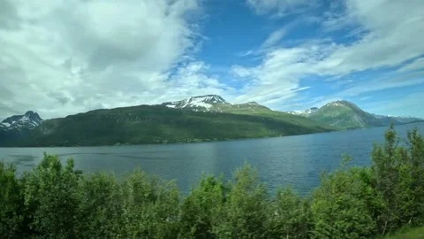 Driving side window view of blue fjord and snow capped mountains in Norway Stock-Footage 340960150