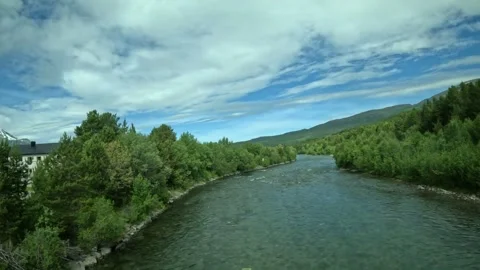 Driving side window view crossing river and white building in Northern Norway Stock-Footage 340960139