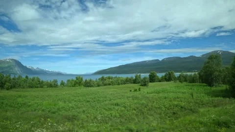 Driving side window view of fields, fjord, and mountains in Northern Norway Stock-Footage 340960143