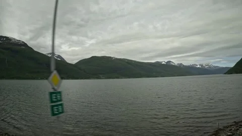 Driving side window view of fjord passing yellow road sign in Northern Norway Vidéo 341272654
