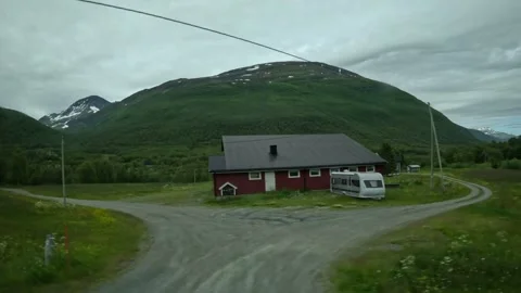 Driving side window view of red barn with caravan and mountains in Norway Stock Footage 341272659