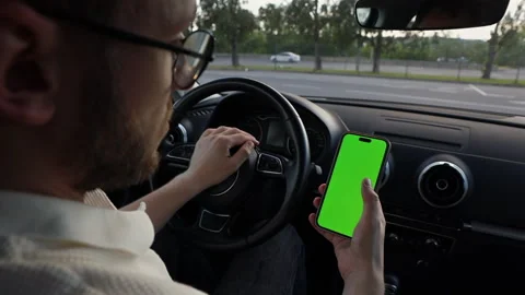 Driving with a Smartphone: A Person Engaged in Using a Green Screen Phone While Stock Footage 314460155