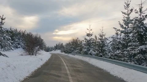 Driving on a snow covered road in a forest at sunset, sunrise Stock Footage 325616129