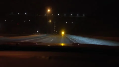 Driving at snowy city intersection at night with traffic signals Stock Footage 329536558