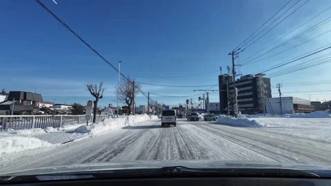 Driving snowy road toward intersection with traffic lights in Asahikawa Stockbeeldmateriaal 333314230