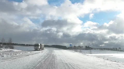 Driving on a snowy road in winter with clouds and trees near the traffic signs Stock-Footage 325793259