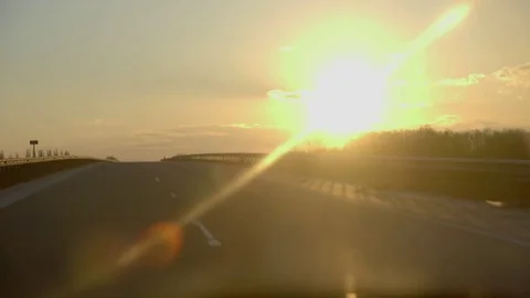 Driving into a sunset on highway with flare Stockbeeldmateriaal 73107169