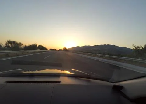 Driving to sunset at Highway view from inside of car. Travel concept Stock Photos