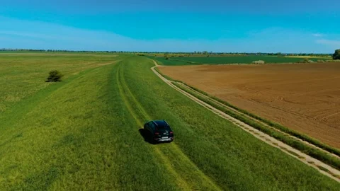 Driving SUV across rough terrain between crop fields. Moving vehicle along Stock Footage 311933573