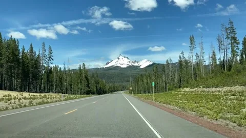 Driving through forest towards a snow-capped mountain in rural Central Oregon. Stock Footage
