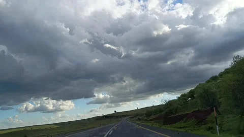 Driving Through Green Hills Under Dramatic Cloudy Sky 動画素材 335489330
