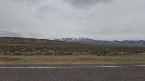 Driving through open land with snow covered mountains Stock Footage 167570258