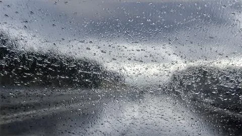 Driving through a rainstorm on a cloudy day with water droplets on the wind.. Stock Photos