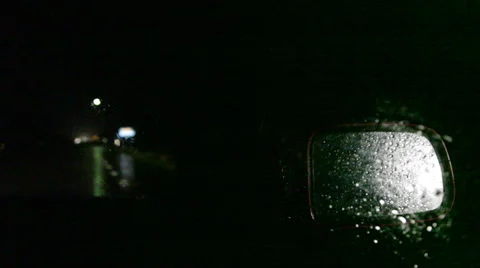 Driving through a rainy night in a car - close up of the rearview mirror Stock Footage