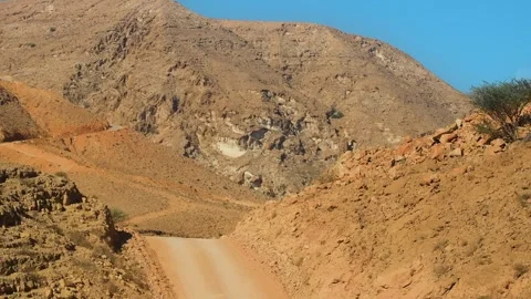 Driving through the rugged Hajar Mountains of Oman on a winding dirt road. Video stock 318623634