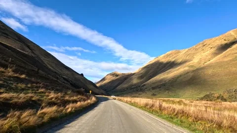 Driving through scenic mountain valley with golden grass and blue sky footage Stock-Footage 332630068