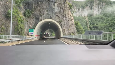 Driving Through a Short Rock Tunnel into a Long Illuminated Highway Tunnel Stock Footage 341396293