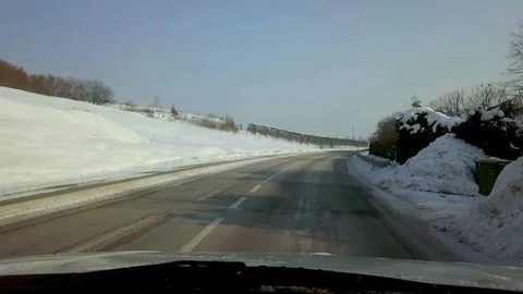 Driving through snowy countryside on cold winter morning with sun rising. Stock Footage 86555848