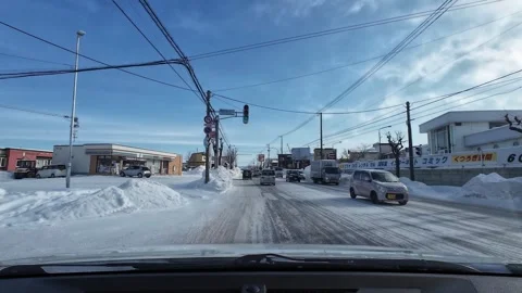 Driving through snowy intersection with traffic and trucks in Asahikawa Видео 333314178