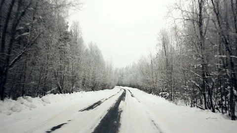 Driving through the winter forest on snowy road, first view. Camera outside the Stock Footage 99885741