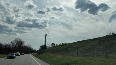 Driving Toward Smokestack Under Cloudy Sky on Quiet Road Stock Footage 332132166
