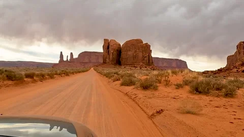 Driving Toward Three Sisters and Stagecoach Buttes in Monument Valley Stock Footage 309049583