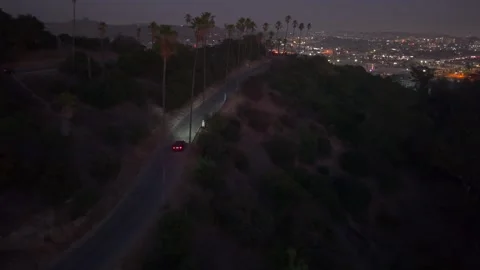 Driving toward view-point skyline at sunset. Car headlights shine towards LA Stock Footage 324956100