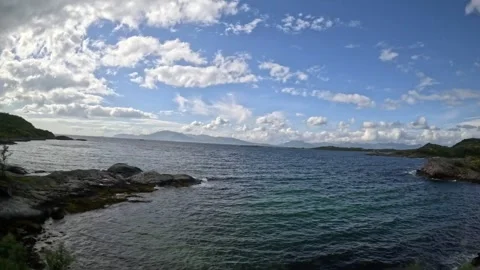 Driving tracking shot along rocky sea coast under blue sky in Norway Vidéo 343833891