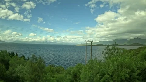 Driving tracking shot along scenic coastal fjord with utility poles in Norway Vidéo 343833886