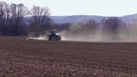 Driving tractor in cloud of dust loosening soil at spring Stock Footage 146689218